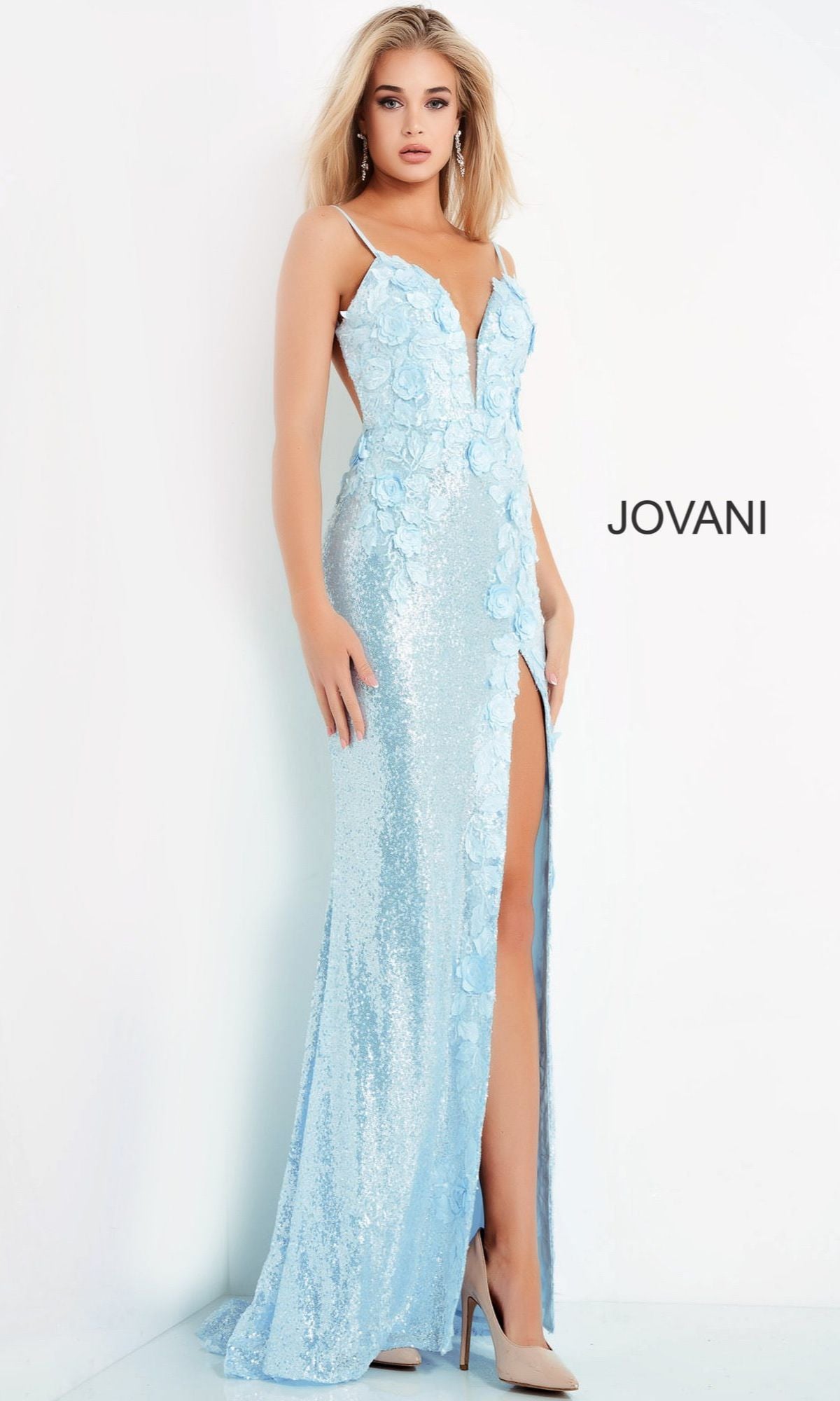 A woman poses against a white backdrop with the Jovani logo, wearing the Long Sequin Jovani Prom Dress with appliques—a light blue, floor-length gown featuring floral appliqué, sequins, a thigh-high slit, and thin shoulder straps.